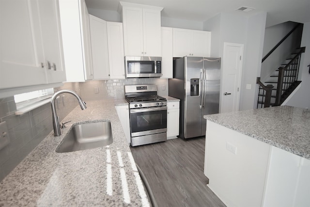 kitchen with appliances with stainless steel finishes, dark hardwood / wood-style floors, white cabinetry, and sink