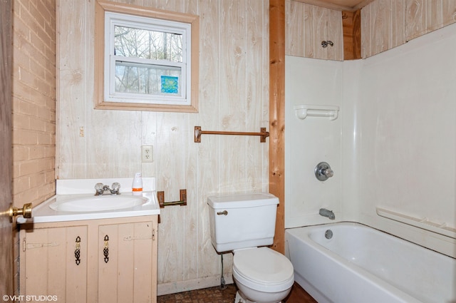 full bathroom featuring brick wall, toilet, wooden walls, shower / washtub combination, and vanity