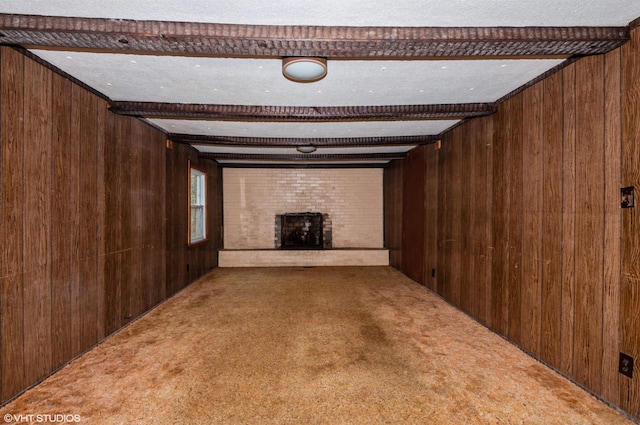 unfurnished living room featuring beam ceiling, wooden walls, carpet, and a brick fireplace