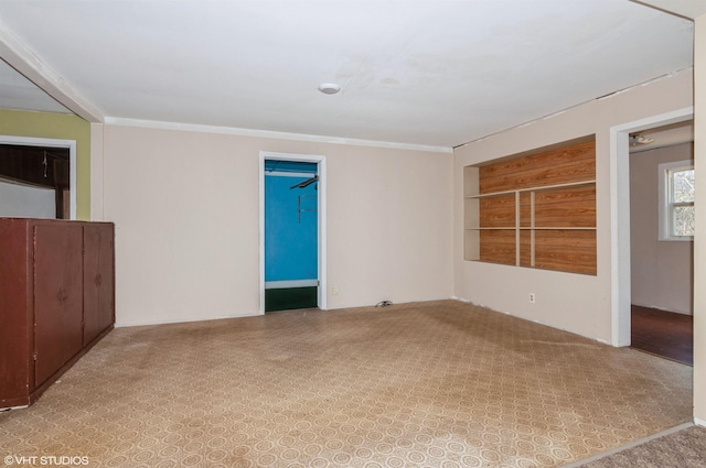 spare room featuring built in shelves and ornamental molding