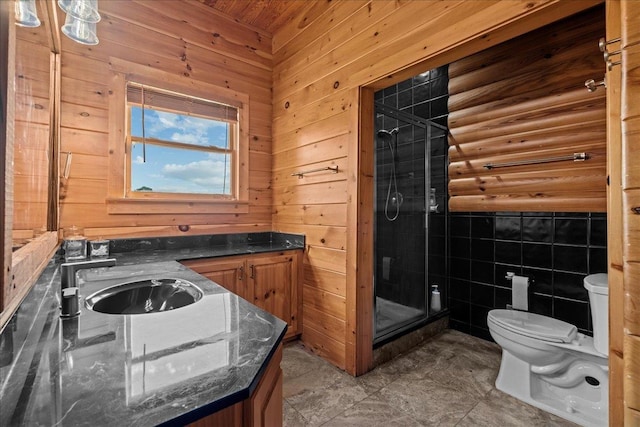 bathroom featuring tile patterned floors, toilet, wooden walls, vanity, and a shower with shower door