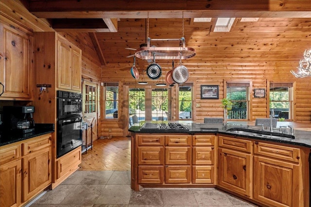 kitchen with vaulted ceiling with skylight, double oven, sink, log walls, and decorative light fixtures