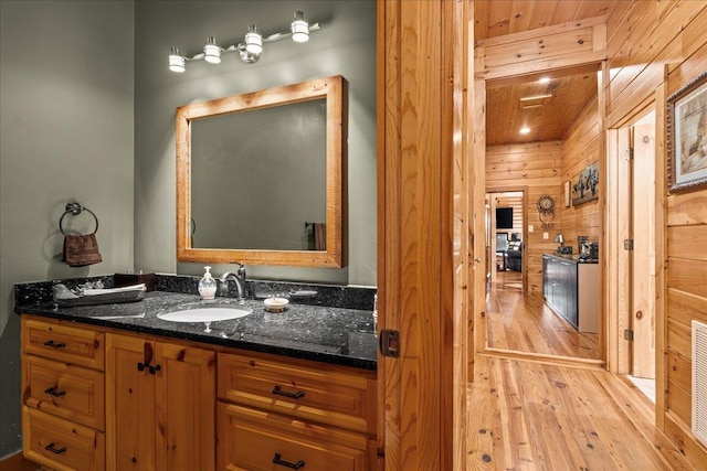 bathroom featuring hardwood / wood-style floors, vanity, and wooden walls