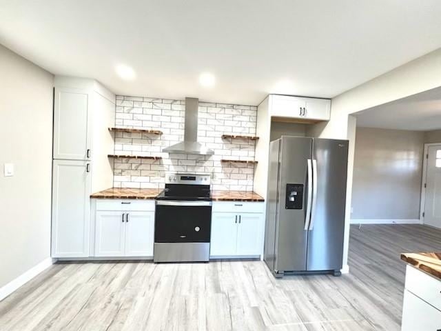 kitchen with wall chimney exhaust hood, appliances with stainless steel finishes, tasteful backsplash, white cabinetry, and butcher block counters