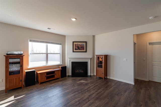 unfurnished living room with visible vents, a fireplace, baseboards, and dark wood-style flooring