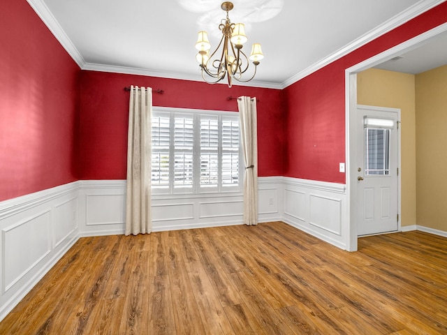 unfurnished dining area with crown molding, a chandelier, and hardwood / wood-style flooring