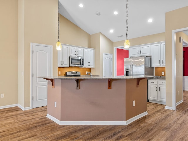 kitchen with white cabinetry, a breakfast bar, an island with sink, and stainless steel appliances