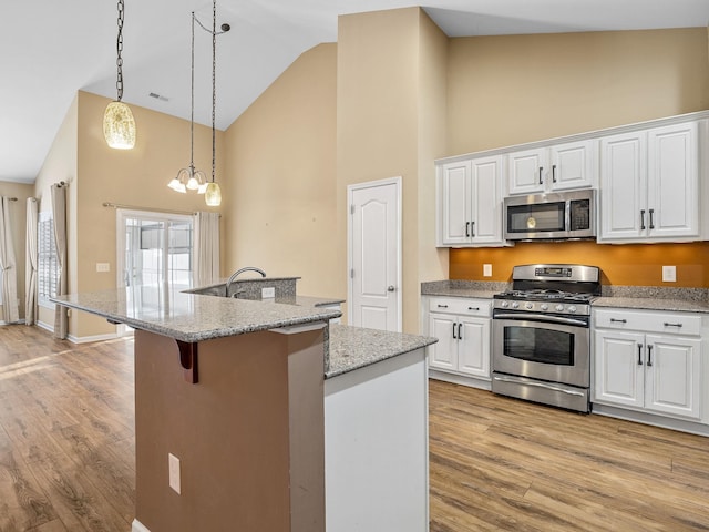 kitchen featuring pendant lighting, stainless steel appliances, and white cabinetry