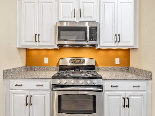 kitchen with light stone counters, white cabinetry, and appliances with stainless steel finishes