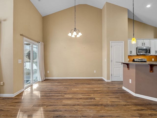 interior space with a breakfast bar, white cabinets, pendant lighting, and a notable chandelier