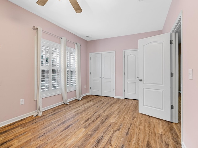 unfurnished bedroom with ceiling fan, two closets, and light wood-type flooring