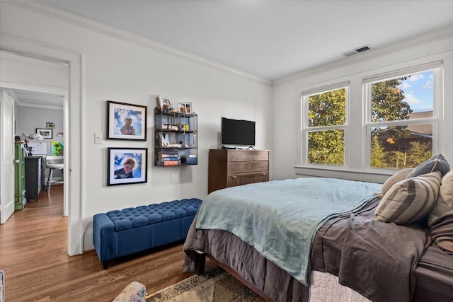 bedroom with ornamental molding and dark hardwood / wood-style floors