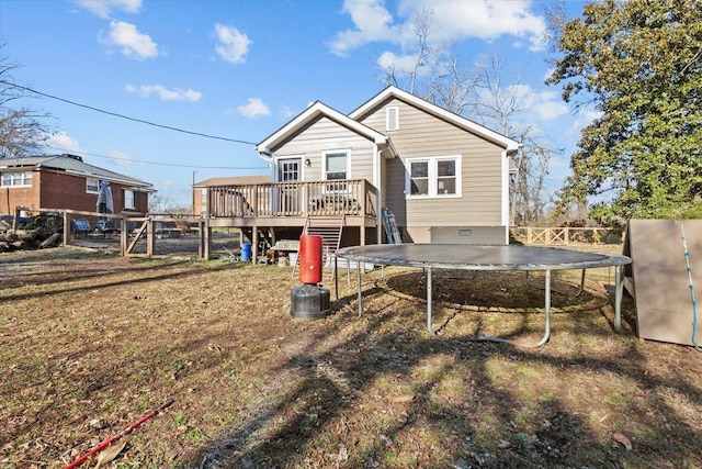 back of property with a trampoline and a wooden deck