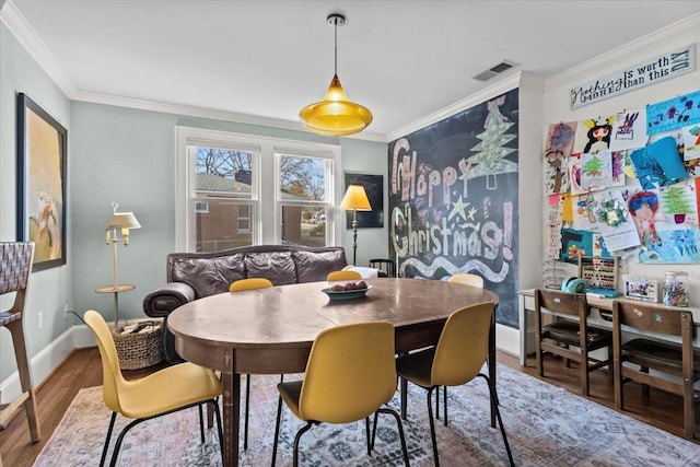 dining area with hardwood / wood-style floors and crown molding