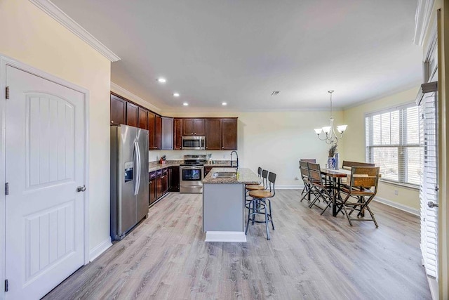 kitchen with sink, light stone counters, an island with sink, pendant lighting, and appliances with stainless steel finishes