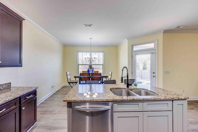 kitchen with dishwasher, light stone counters, sink, and an inviting chandelier