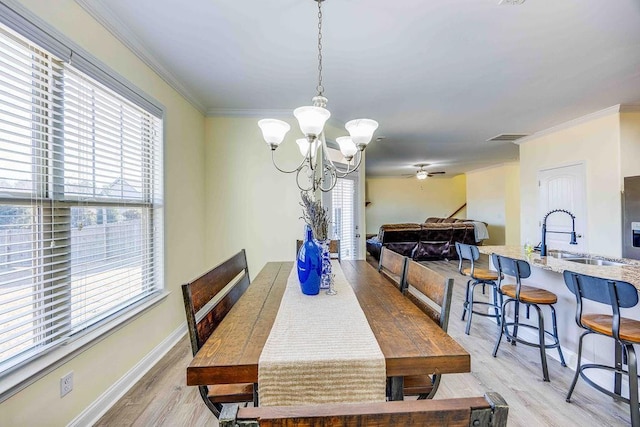 dining area featuring crown molding, sink, ceiling fan with notable chandelier, and light hardwood / wood-style flooring