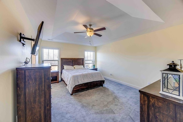 bedroom with a raised ceiling, ceiling fan, and light colored carpet