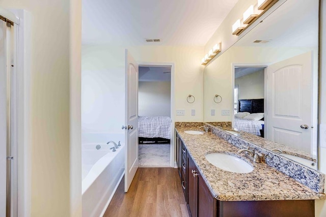 bathroom with a tub to relax in, vanity, and hardwood / wood-style flooring