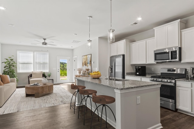 kitchen featuring white cabinetry, an island with sink, hanging light fixtures, and appliances with stainless steel finishes