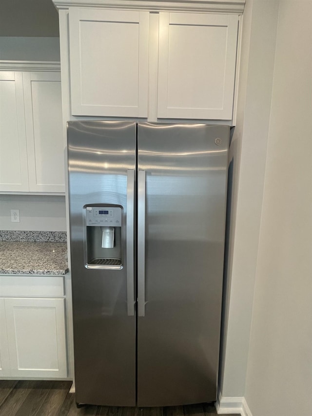 kitchen with stainless steel fridge, dark hardwood / wood-style flooring, white cabinets, and light stone counters