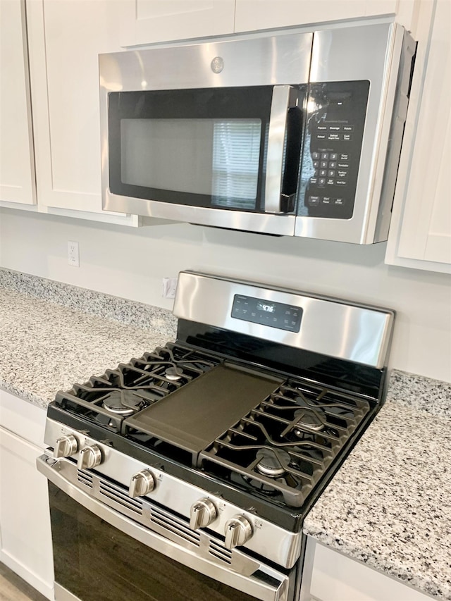 details with light stone counters, white cabinetry, and stainless steel appliances