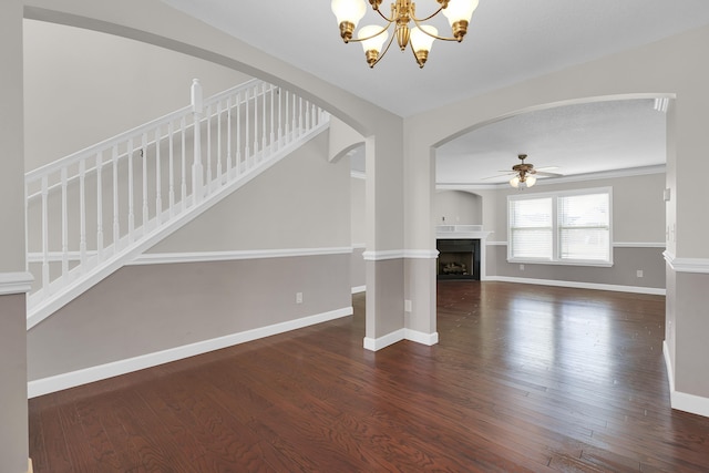 unfurnished living room featuring ceiling fan with notable chandelier and dark hardwood / wood-style flooring