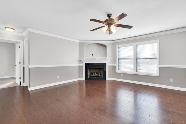 unfurnished living room with dark wood-type flooring, ceiling fan, crown molding, and a tiled fireplace