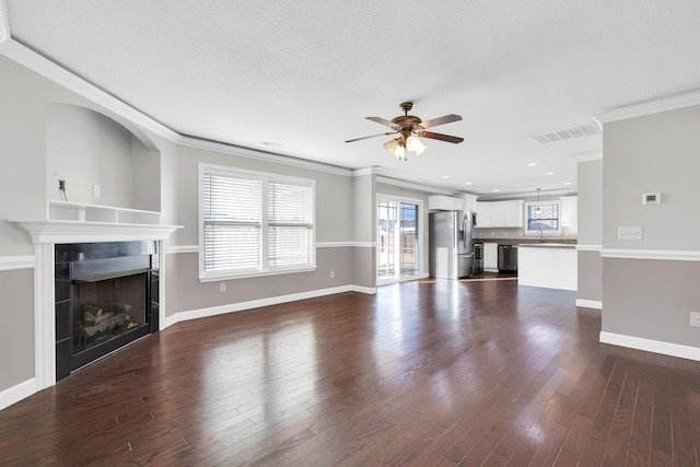 unfurnished living room featuring a wealth of natural light, a fireplace, ceiling fan, and crown molding