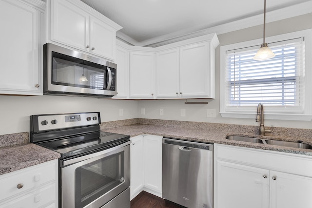 kitchen featuring light stone counters, stainless steel appliances, sink, white cabinets, and hanging light fixtures