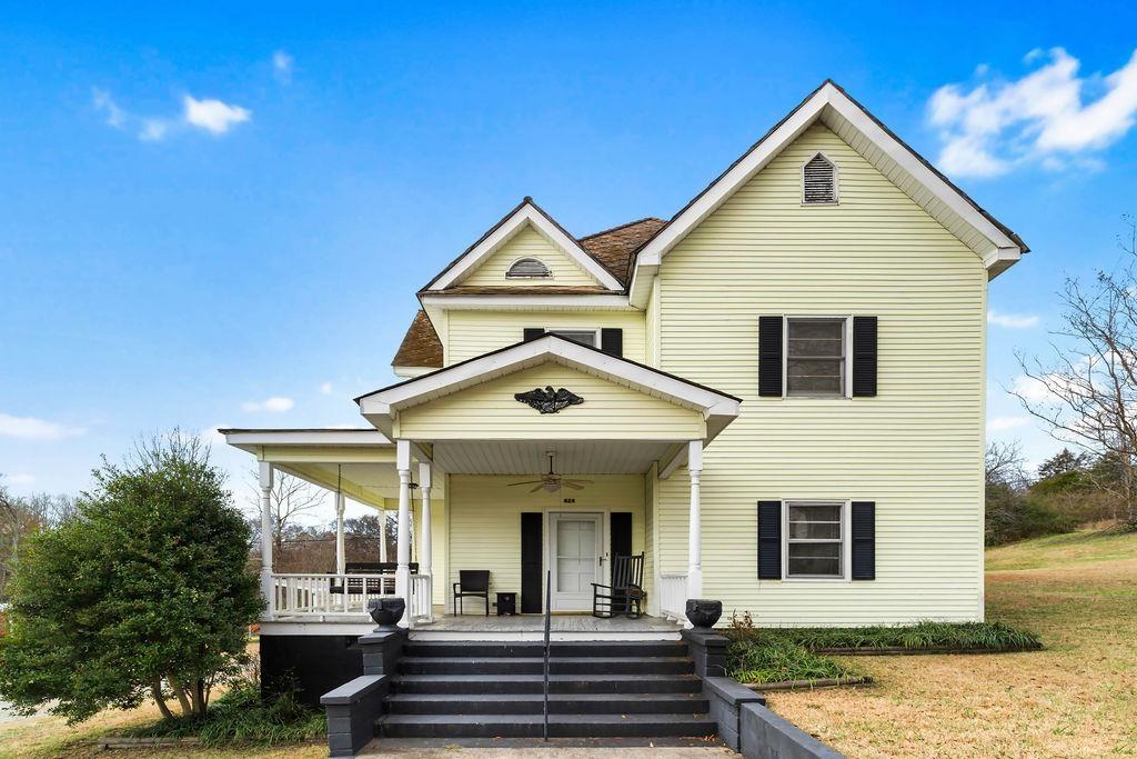 view of front of property with ceiling fan, a front lawn, and covered porch