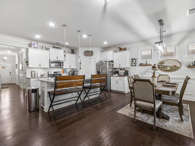 dining area with crown molding, sink, and dark hardwood / wood-style floors