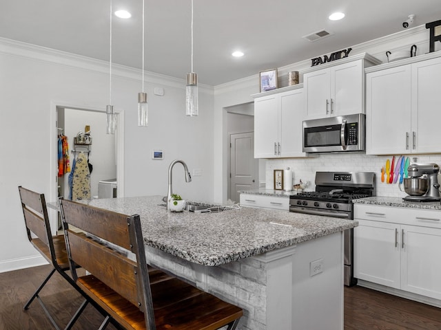 kitchen featuring sink, hanging light fixtures, stainless steel appliances, an island with sink, and white cabinets