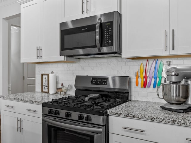 kitchen with decorative backsplash, white cabinetry, light stone countertops, and appliances with stainless steel finishes