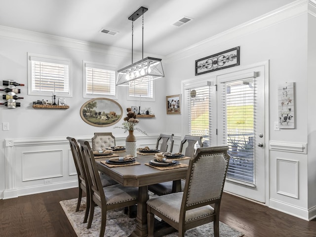 dining area with a healthy amount of sunlight, an inviting chandelier, ornamental molding, and dark wood-type flooring