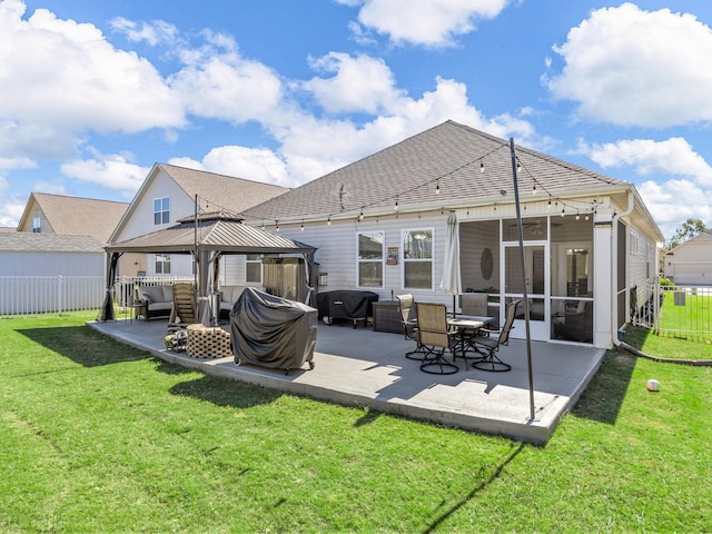 back of house featuring a gazebo, a sunroom, a patio area, and a lawn