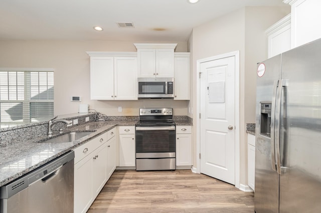 kitchen featuring sink, light hardwood / wood-style flooring, appliances with stainless steel finishes, stone countertops, and white cabinetry