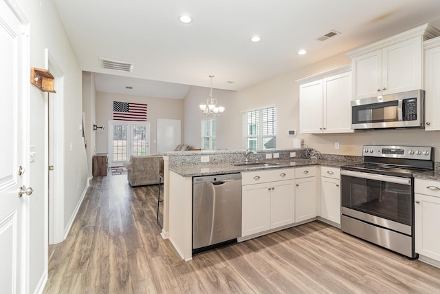 kitchen featuring an inviting chandelier, white cabinets, sink, appliances with stainless steel finishes, and kitchen peninsula