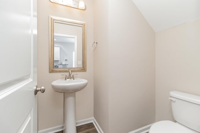 bathroom featuring hardwood / wood-style flooring, sink, lofted ceiling, and toilet