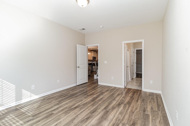 unfurnished bedroom featuring dark hardwood / wood-style floors and ensuite bathroom