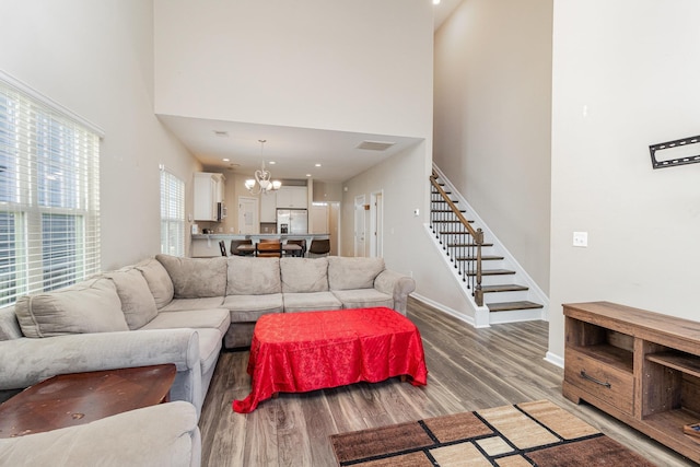 living room featuring hardwood / wood-style floors, a towering ceiling, and a notable chandelier