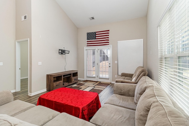 living room with a towering ceiling and hardwood / wood-style flooring