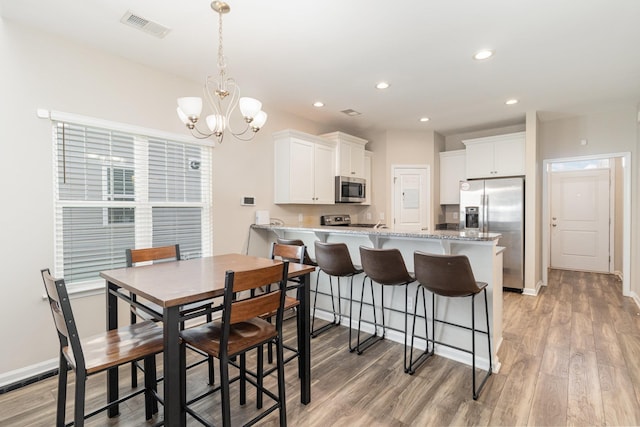 dining area featuring an inviting chandelier and light hardwood / wood-style flooring