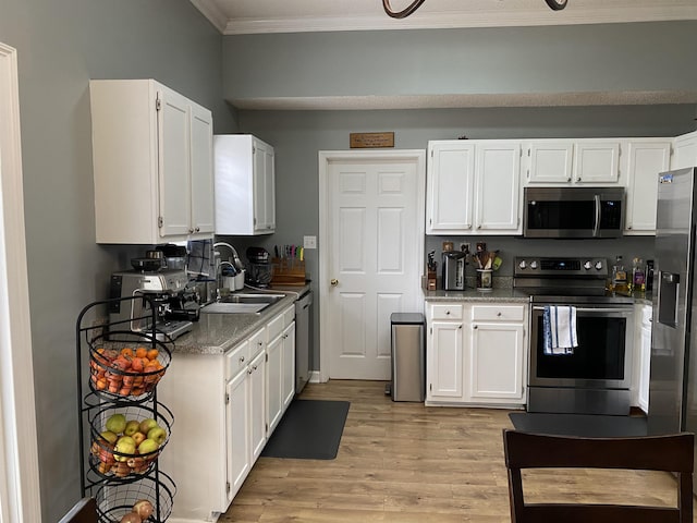 kitchen with light wood-type flooring, ornamental molding, stainless steel appliances, sink, and white cabinets