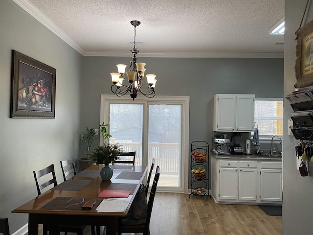 dining area featuring sink, light wood-type flooring, a textured ceiling, and a chandelier