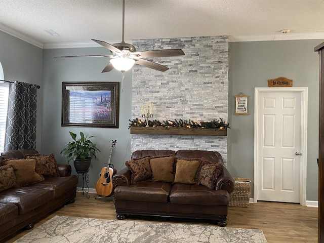 living room featuring ceiling fan, light wood-type flooring, a textured ceiling, and ornamental molding