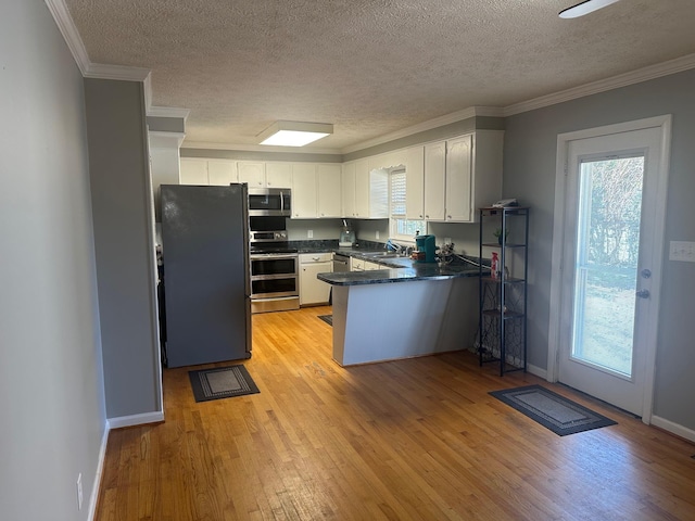 kitchen featuring kitchen peninsula, light wood-type flooring, a textured ceiling, appliances with stainless steel finishes, and white cabinetry