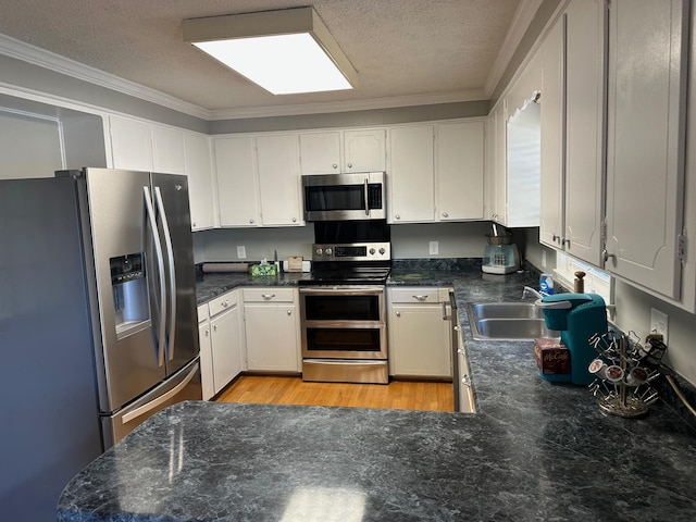 kitchen with white cabinets, appliances with stainless steel finishes, crown molding, and sink