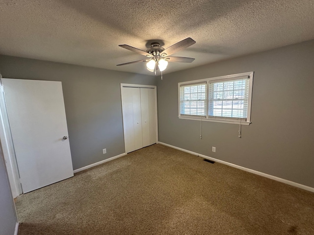 unfurnished bedroom with carpet flooring, ceiling fan, a closet, and a textured ceiling