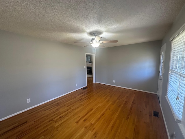 empty room featuring hardwood / wood-style floors, a textured ceiling, a wealth of natural light, and ceiling fan